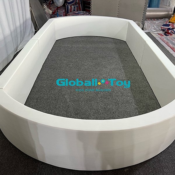 Piscina ovale con palline morbide bianche per attività per bambini.